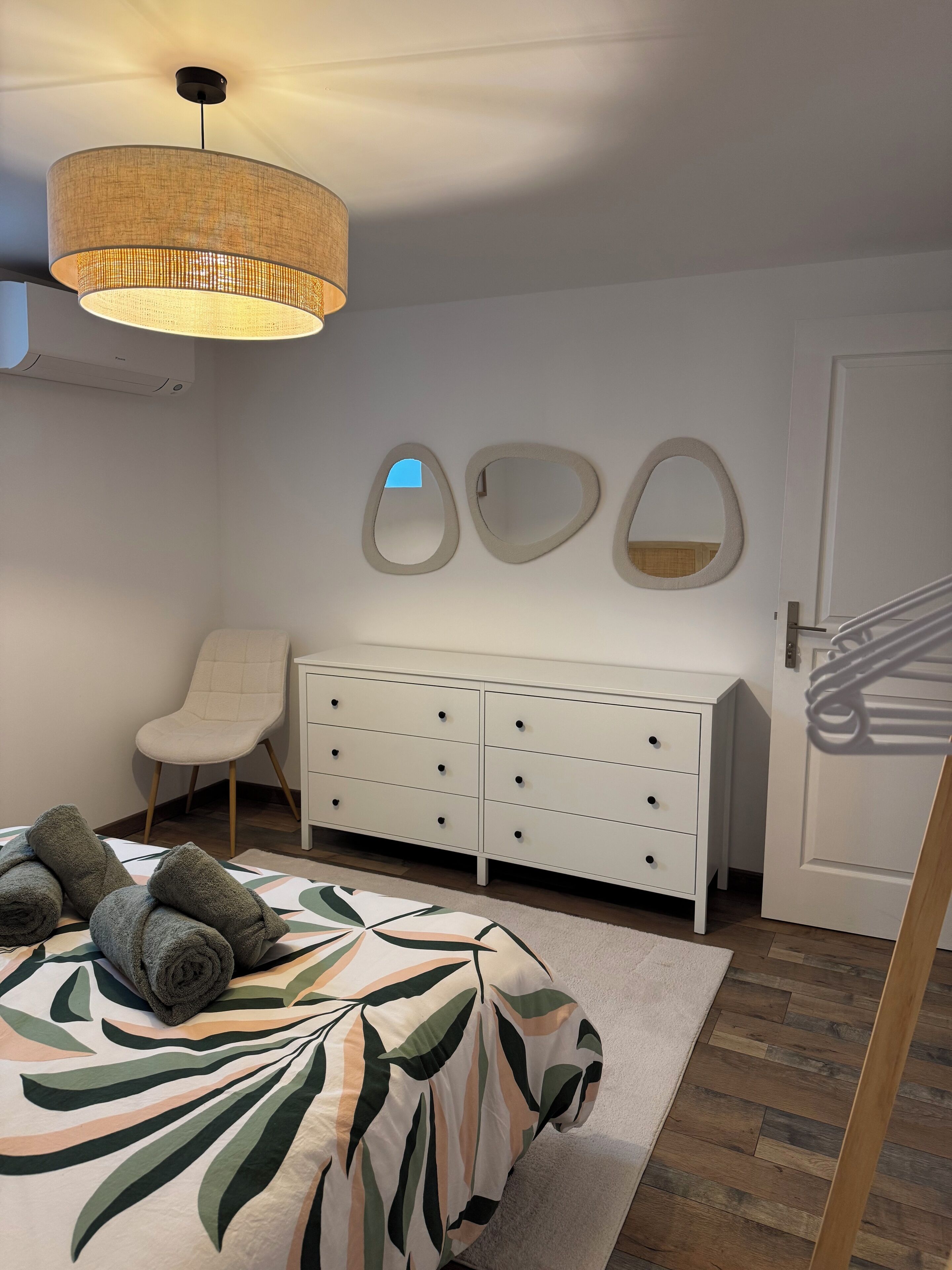 Ein Schlafzimmer mit Bett, Kommode, Stuhl und Tür.