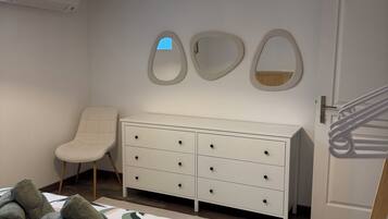 Ein Schlafzimmer mit Bett, Kommode, Stuhl und Tür.