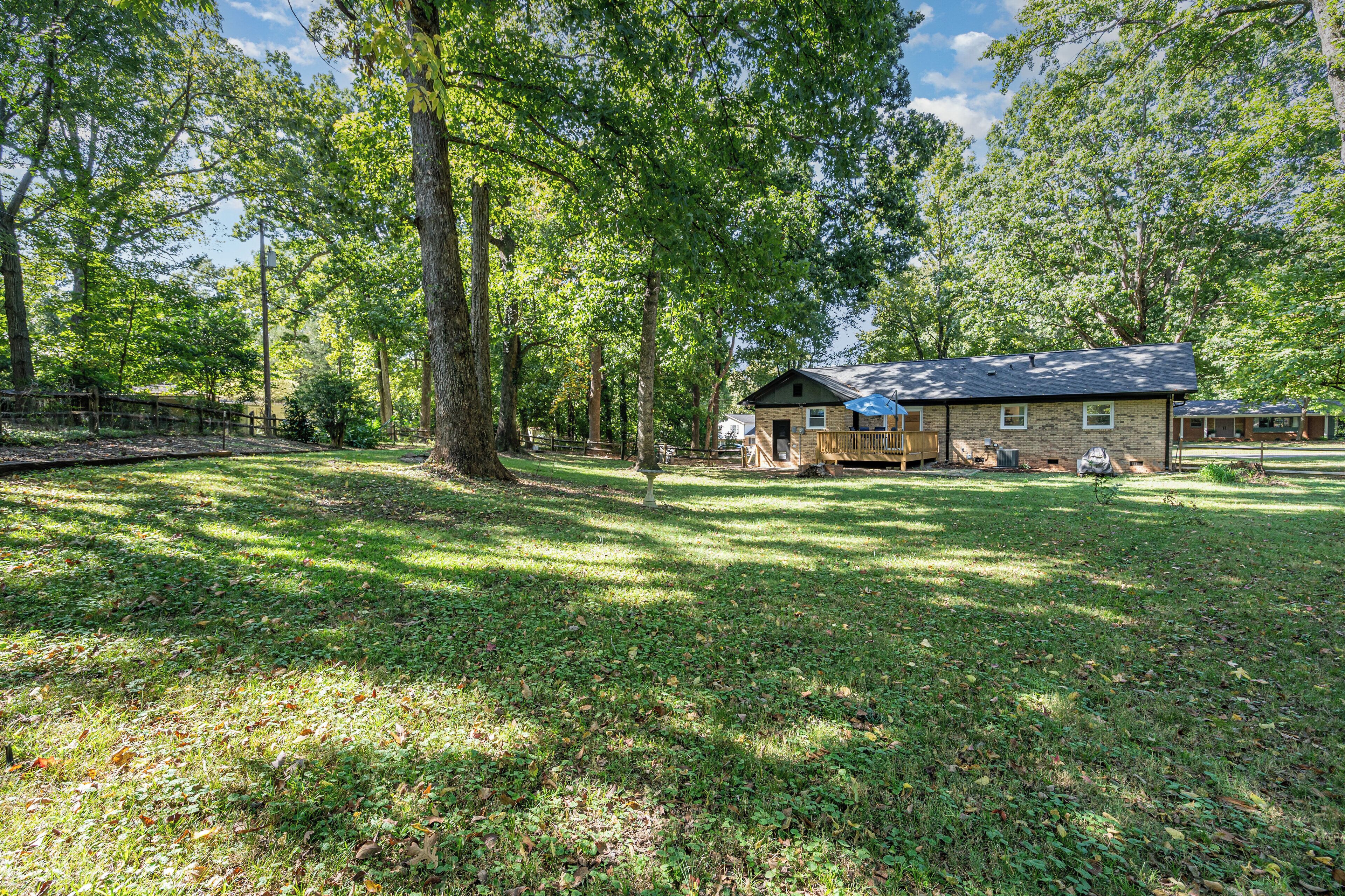 A rustic cabin with a porch, surrounded by a wooded area and a small clearing.