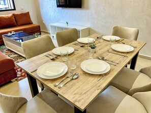 Un coin repas avec une table en bois dressée pour quatre personnes, entourée de chaises de couleur beige.