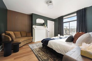Ett modernt sovrum med en säng, en soffa, ett litet bord och en öppen spis.