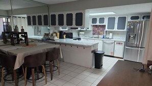 Une cuisine dotée d’un îlot central, de meubles blancs et d’un réfrigérateur en acier inoxydable.