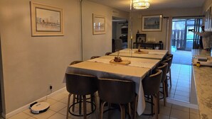 Un espace repas comprenant une longue table, des chaises et un luminaire suspendu au plafond.
