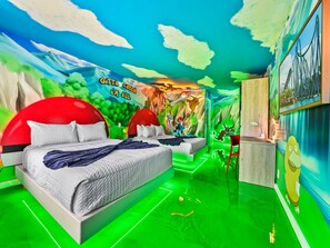 Een kleurrijke kinderkamer met muurschildering, twee rode bedden, een bureau en een groene vloer.