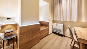 A modern, well-lit room with wooden flooring, a built-in bench, a table, and a wall-mounted air conditioner. - Your urban oasis in the heart of Chania Town,a blend of convenience and comfort. (Chania)