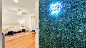 A bedroom with a bed, bedside tables, a ceiling fan, and a neon sign on the wall. - Spacious 4BR Home - King Suite - Family Friendly - Near Dallas Attractions (Dallas)