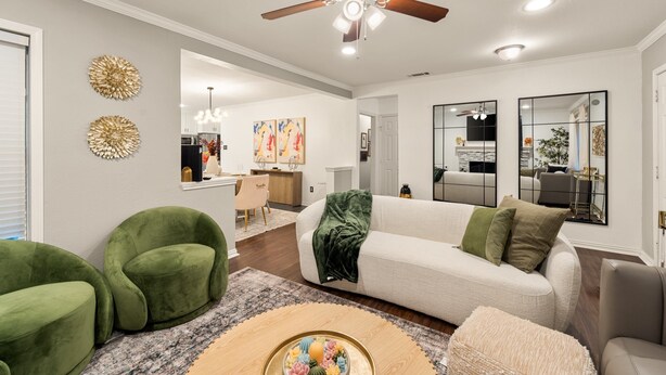 A living room with a ceiling fan, a white sofa, green armchairs, and a coffee table with decorative items. - Spacious 4BR Home - King Suite - Family Friendly - Near Dallas Attractions (Dallas)