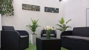 Una habitación con muebles de mimbre, césped artificial y plantas en macetas.