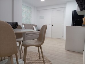Een moderne woonkamer met een bank, stoelen, een eettafel en een keukenhoek.