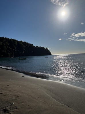 Una playa con cielo despejado, aguas tranquilas y una costa distante.