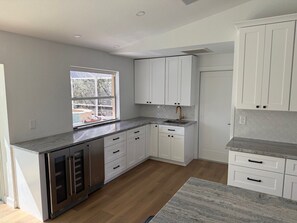 A modern kitchen with white cabinetry, a granite countertop, and a window providing natural light. - Beautiful sanibel home (Sanibel)