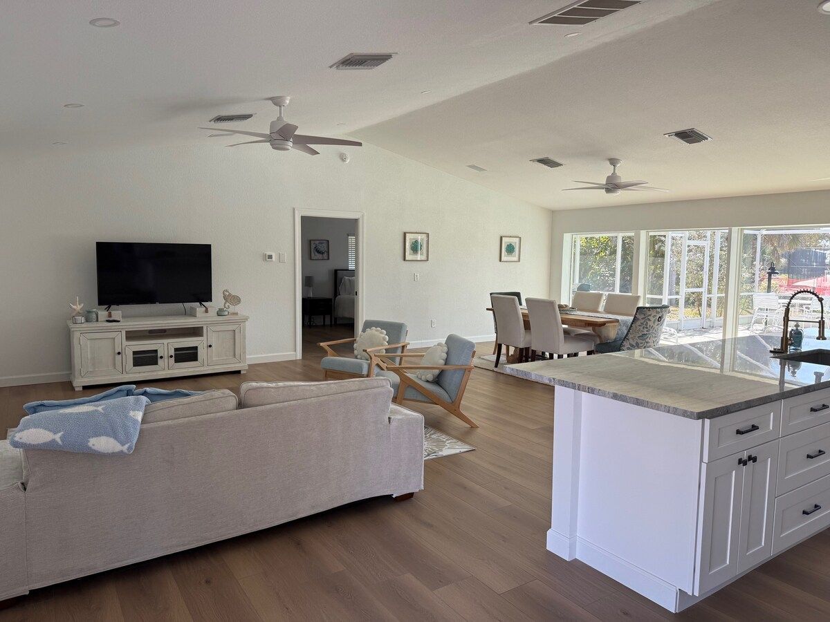 A spacious living area with a sofa, chairs, a TV, and a kitchen island.