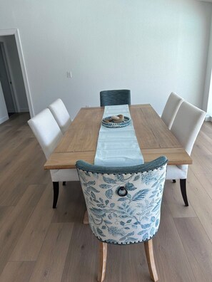 A dining table with a light blue table runner, white upholstered chairs, and a patterned cushion on one chair. - Beautiful sanibel home (Sanibel)
