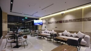 Eine moderne Lobby mit einer Couch, Sesseln, einem Couchtisch und einem Fernsehbildschirm.