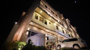 Ein mehrstöckiges Hotel mit gut beleuchtetem Eingang und einem geparkten Auto davor.