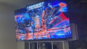 Ein Flachbildfernseher ist an einer Ziegelwand befestigt. Darunter befindet sich ein Regal mit Spielesammlungen.