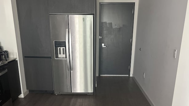 Eine moderne Küche mit einem Edelstahlkühlschrank, Holzschränken und einem dunklen Holzboden.