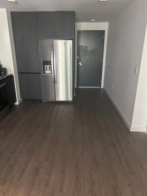 Eine moderne Küche mit einem Edelstahlkühlschrank, Holzschränken und einem dunklen Holzboden.