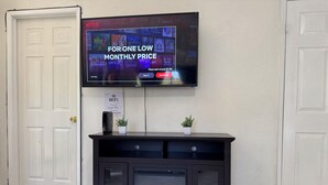 A living room with a fireplace, a television mounted on the wall, and a WiFi sign.