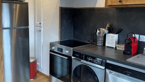 A modern kitchen with stainless steel appliances, a wooden cabinet, and a black countertop. - Mountain apartment 5 minutes from the center of Saint Gervais les Bains (Saint-Gervais-les-Bains)