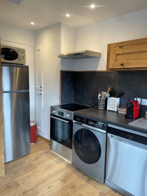 Una cocina moderna con electrodomésticos de acero inoxidable, un mueble de madera y una encimera negra.