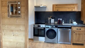 A modern kitchen with stainless steel appliances, wooden cabinets, and a built-in oven. - Mountain apartment 5 minutes from the center of Saint Gervais les Bains (Saint-Gervais-les-Bains)