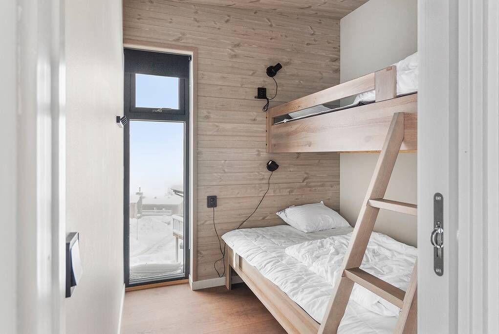 Ein kleines Zimmer mit Etagenbett, einer Schiebetür zu einem Außenbereich und einem kleinen Schreibtisch mit Stuhl.