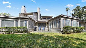 Une maison moderne dotée d’un porche abrité, d’une cheminée et d’une pelouse bien entretenue.