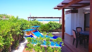 Un espace extérieur aménagé avec une piscine, des sièges et une vue sur la plage.