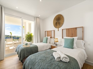 A hotel room with two beds, a large window with a view, a ceiling fan, and a potted plant. - Stylish 2-bedroom Apartment in Casares (Casares)