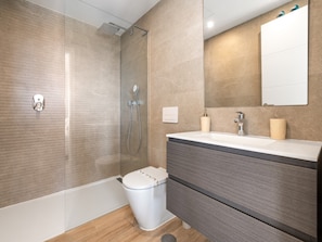 A modern bathroom with a glass-enclosed shower, a white toilet, and a vanity with a mirror. - Stylish 2-bedroom Apartment in Casares (Casares)