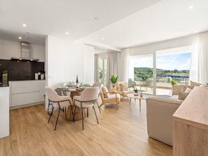 A modern living space with a dining area, seating, and a view of the outdoors. - Stylish 2-bedroom Apartment in Casares (Casares)