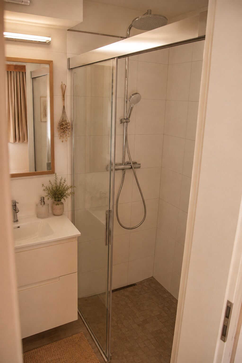 Une salle de bain moderne avec une douche à parois de verre, un lavabo blanc et un miroir.