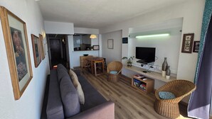 Un salon moderne comprenant un canapé, des fauteuils, une table à manger et un téléviseur.