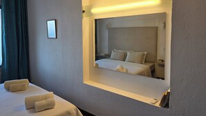 Une chambre d’hôtel avec un grand miroir, un lit avec des oreillers et deux serviettes sur le lit.