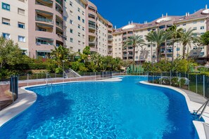 Ein Pool mit geschwungener Form, umgeben von einem Zaun und Palmen.