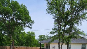Un jardin avec un foyer entouré de chaises Adirondack bleues, une terrasse en bois et une maison en arrière-plan.