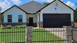 Une maison à deux étages avec un garage, un pilier en pierre et une clôture en métal.