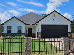 A two-story house with a garage, a stone pillar, and a metal fence.