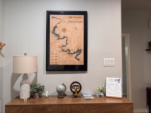 A framed map of Lake Granbury on a wall, a lamp, a globe, a vintage telescope, a small potted plant, and a welcome sign. - Charming, newer, 3 bedroom home with gated boat and watercraft parking in back. (Granbury)