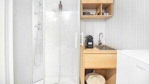 Un baño pequeño con ducha, lavamanos y cafetera.