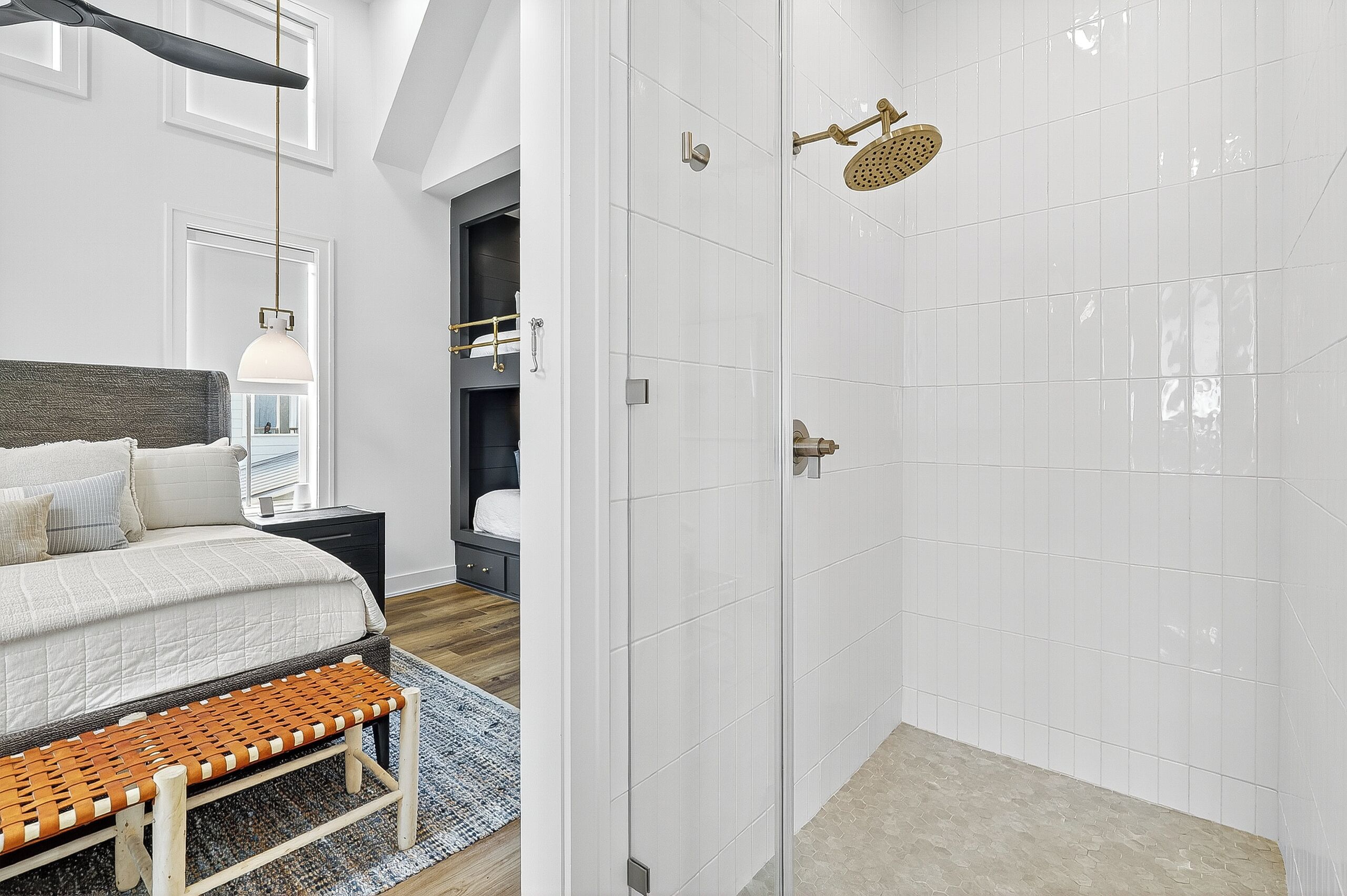A modern bedroom with a large bed, a bench, a nightstand, and a walk-in closet.