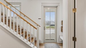 Eine Treppe mit weißen Geländern und Holzstufen, die zu einer Tür mit Glasfenster führt.