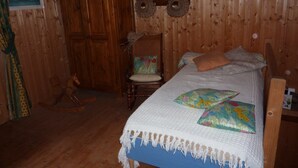 Ein Schlafzimmer einer Holzhütte mit einem Bett, einem Sessel und einer Tür.