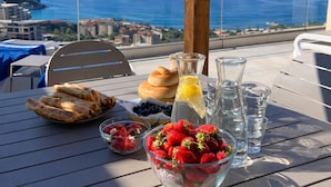 Ein Tisch mit Speisen und Getränken auf einem Balkon mit Blick aufs Meer.