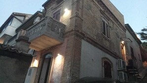 Een historisch gebouw met een gevel van natuursteen, een balkon met decoratieve details en een duidelijke ingang.