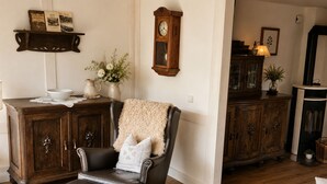 Una sala de estar con un sillón de cuero, un aparador de madera y un reloj en la pared.