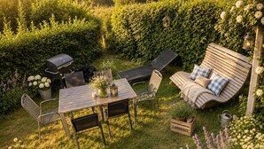 Un jardín cuidado con una mesa y sillas de madera, un banco y una zona de barbacoa.