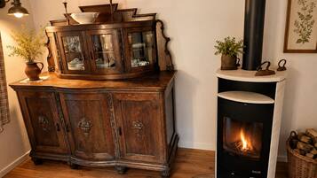 A wooden cabinet with glass doors, a black fireplace with a visible fire, and a wicker basket on the floor.
