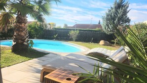 A swimming pool with lounge chairs, a palm tree, and a hedge. - Cosy House With Swimming Pool - Bergerac (5 minutes from downtown) (Bergerac)